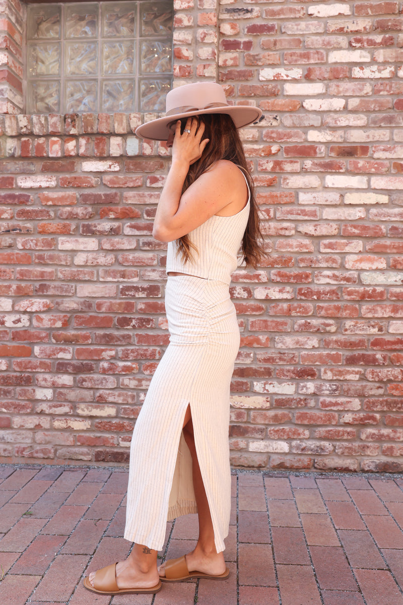 woman wearing a tan hat and two piece linen skirt set with side slit 