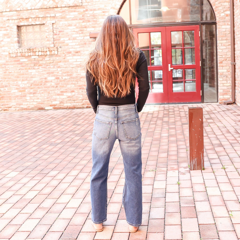 back view of straight fit ankle legth highwaisted mom tight jeans with denim fading at the top